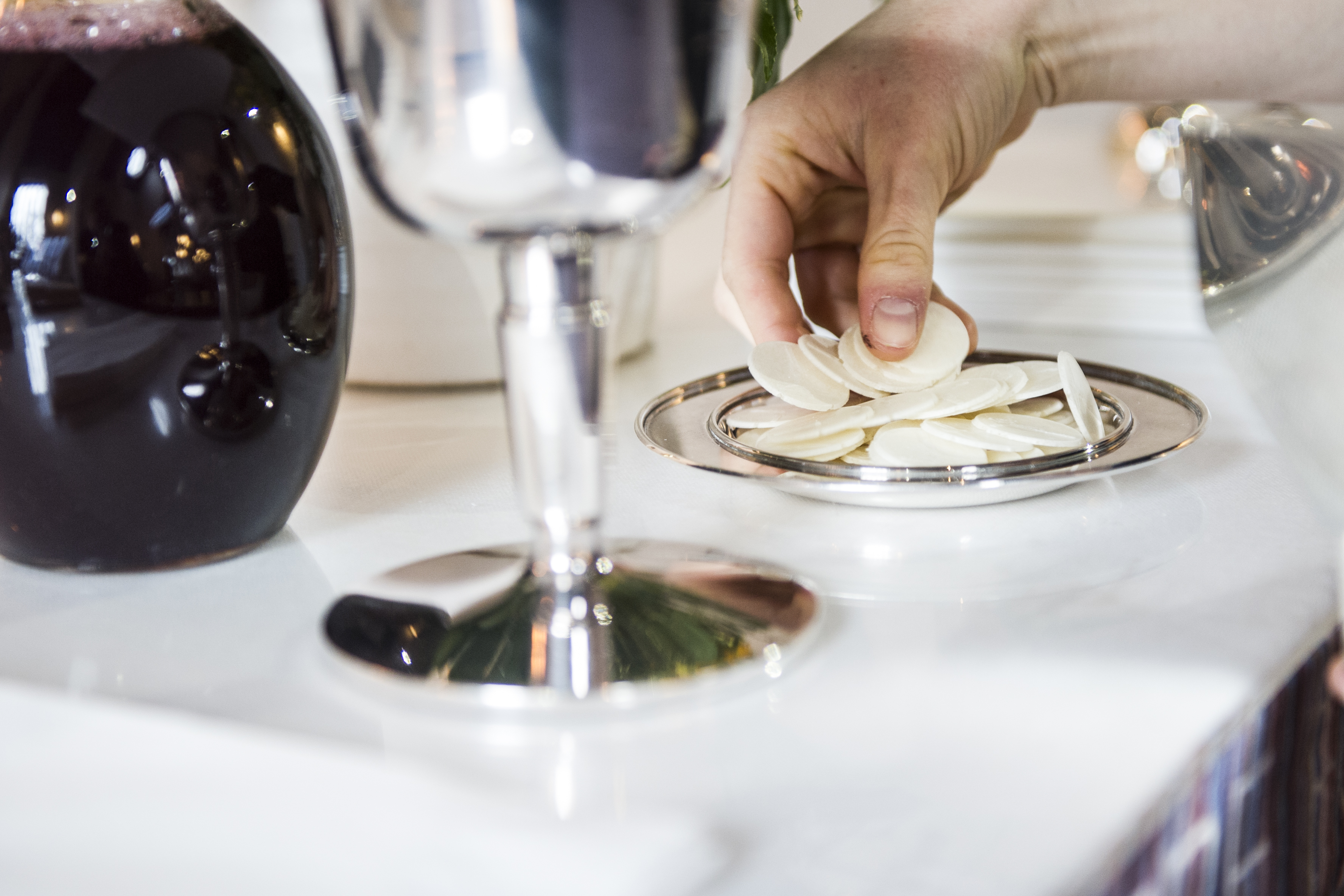 Hånd tager oblat fra alterbordet