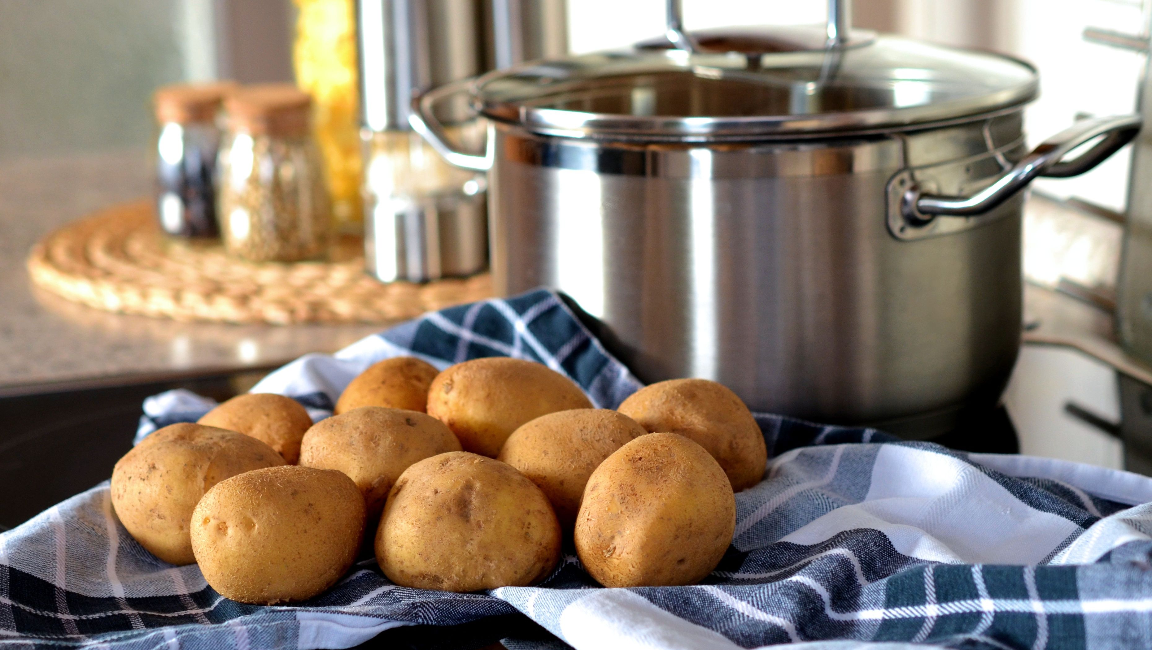 En bunke kartofler foran en gryde.